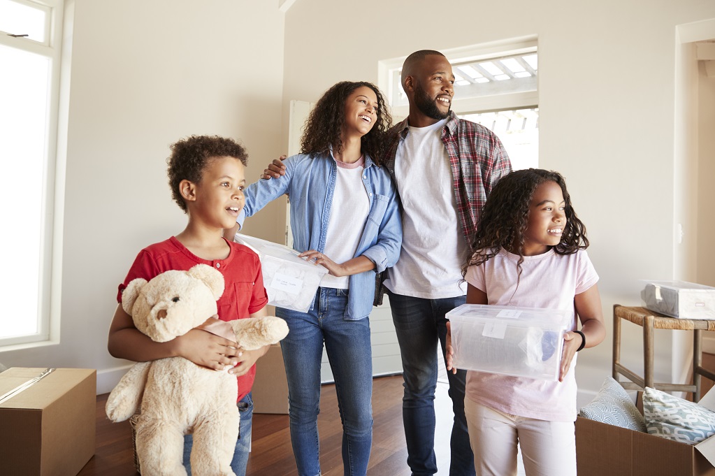 Excited Family Carrying Boxes Into New Home On Moving Day