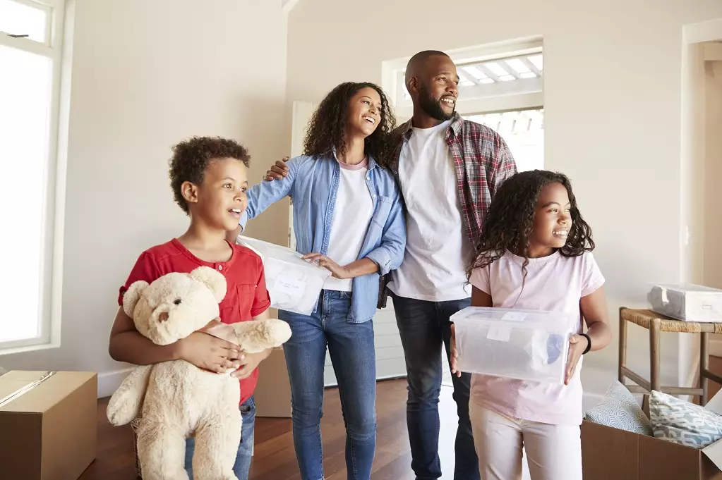 Excited Family Carrying Boxes Into New Home On Moving Day